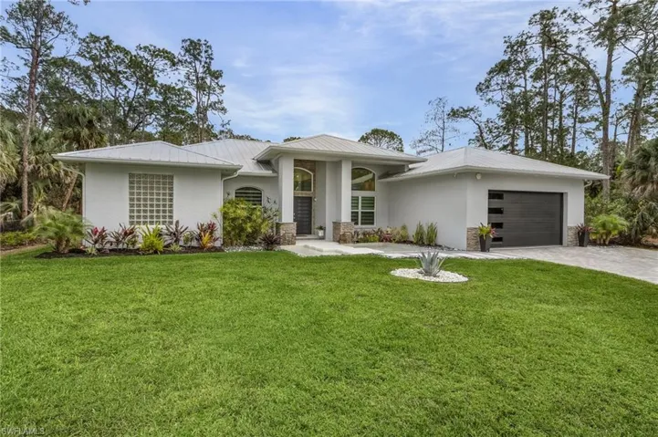 View of front of house with a front yard, new garage door and metal roof