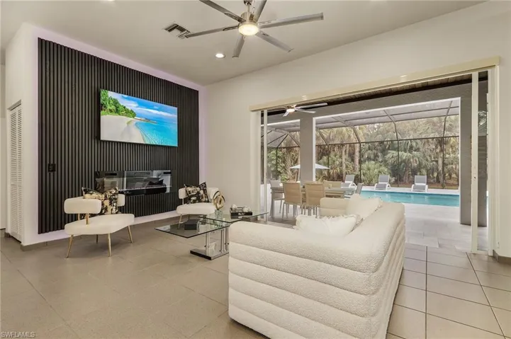 Tiled living room featuring ceiling fan, electrical fireplace and window treatments
