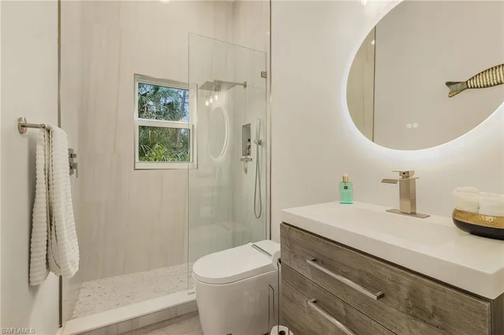 Bathroom featuring walk in shower, floating vanity, and smart bidet/toilet