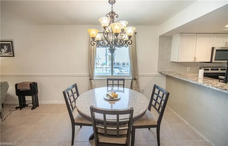 Dining area featuring a central chandelier, tiled flooring, and chair rail molding