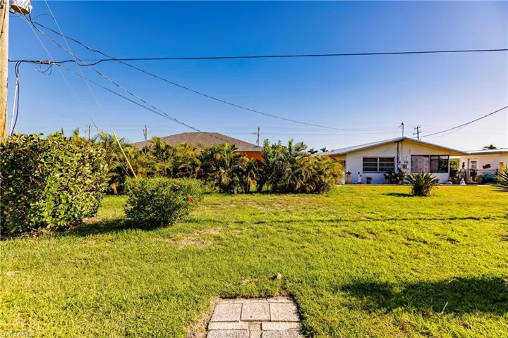 Expansive green lawn with established shrubbery and mature tropical plantings