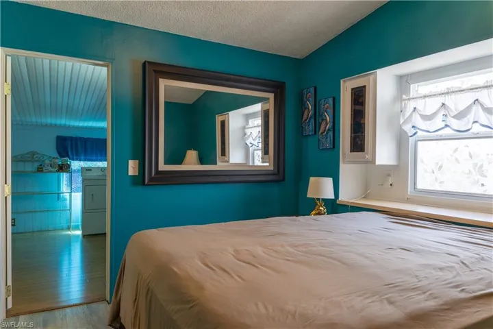 Bedroom with washer / clothes dryer, a textured ceiling, and hardwood / wood-style floors