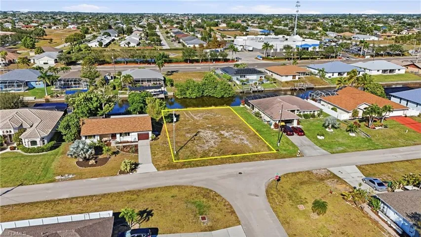 Aerial view of residential area with property boundaries highlighted and a large body of water
