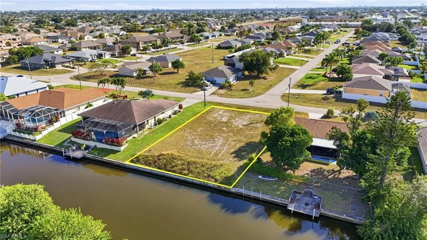 Aerial view of residential area with property boundaries highlighted and a large body of water