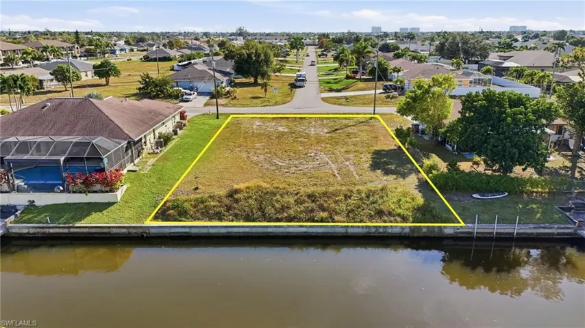 Aerial view of residential area featuring property parcel outlined and a nearby body of water