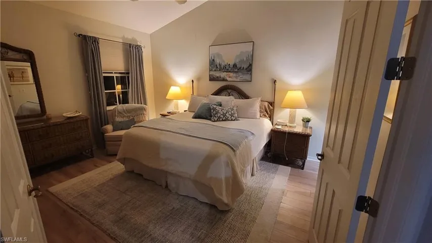 Bedroom with wood finished floors and vaulted ceiling