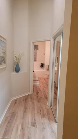 Hallway with light wood-type flooring and a high ceiling
