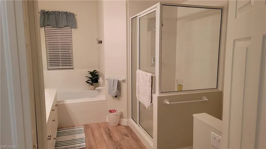 Full bathroom with light wood-style flooring, a stall shower, a bath, and vanity