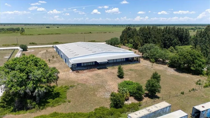 Expansive commercial property featuring a large warehouse building with a metal roof and an extended covered patio