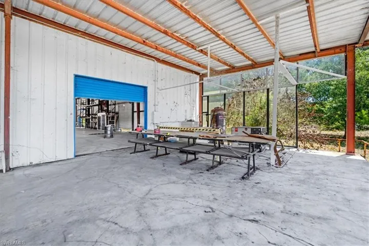 Covered concrete workspace featuring a corrugated metal roof and exposed steel beams