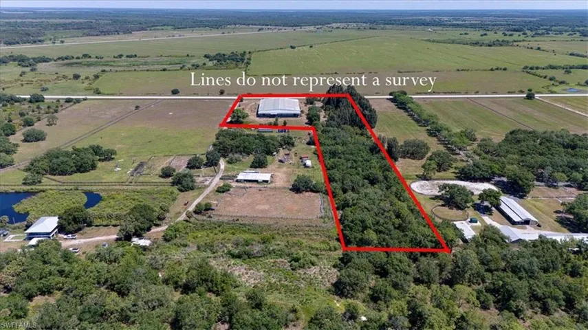 Expansive rural property featuring a large treed area, multiple outbuildings, and a pond
