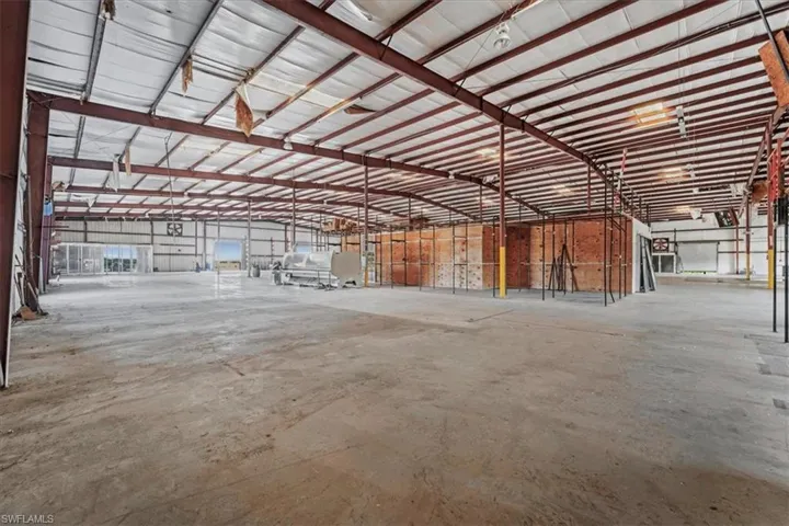 Expansive commercial interior with concrete flooring and exposed metal beam ceiling