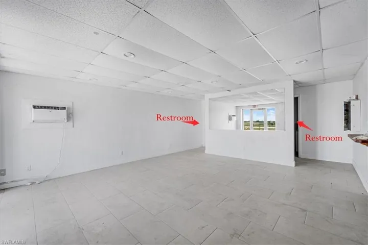 Spacious interior featuring light tile flooring, white walls, and a drop ceiling with recessed lighting