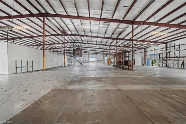 Expansive warehouse interior featuring a high, open ceiling with exposed metal framing and insulation