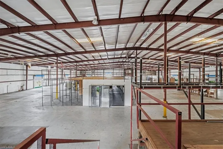 Spacious industrial interior featuring a high, exposed metal beam ceiling with white insulation panels