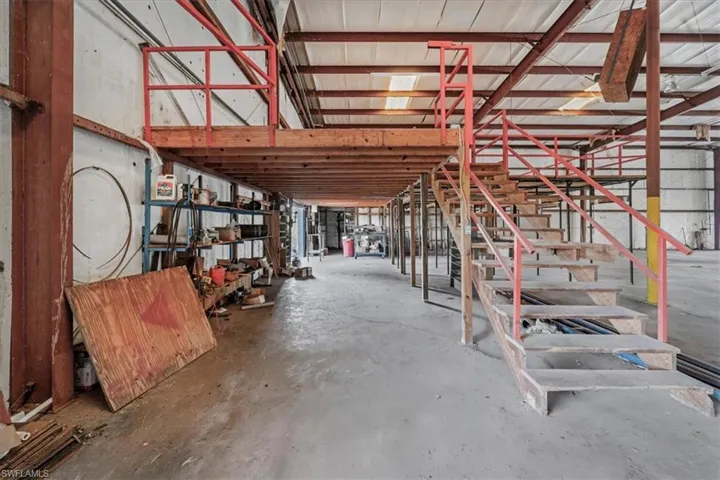 Interior workshop space featuring a multi-level mezzanine structure with wood stairs and red metal railings