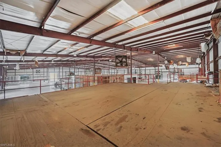 Expansive open-concept industrial space featuring wood-finish flooring, exposed metal beam construction, and high ceilings
