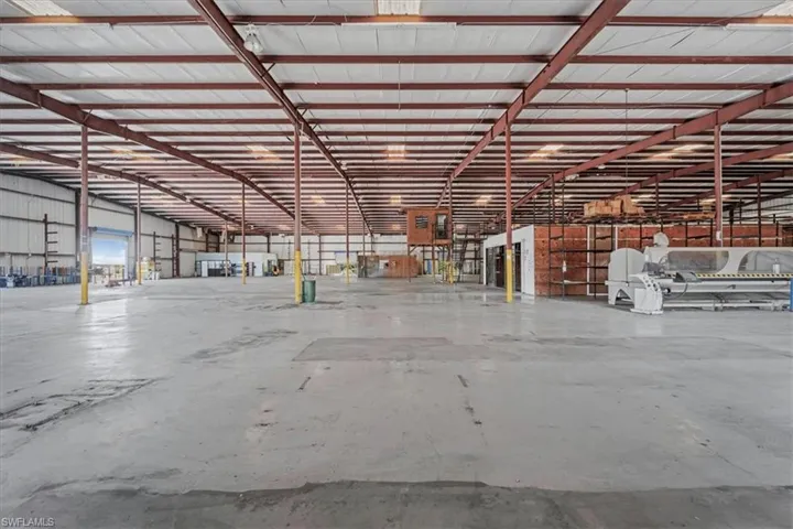 Expansive industrial warehouse featuring a concrete floor, high ceilings with exposed metal beams, and corrugated metal walls