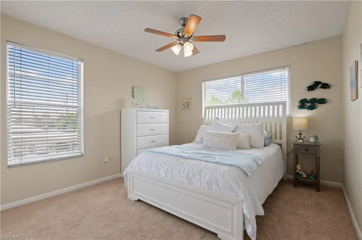 Bedroom with a textured ceiling, ceiling fan, and carpet floors