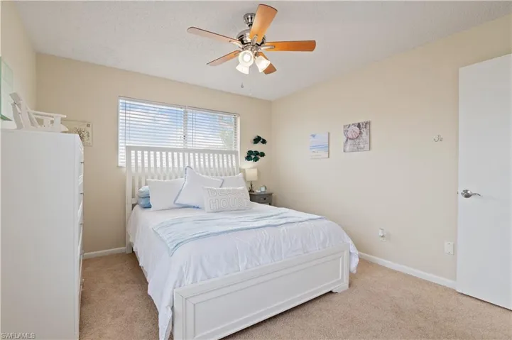Bedroom with ceiling fan, a textured ceiling, and light carpet