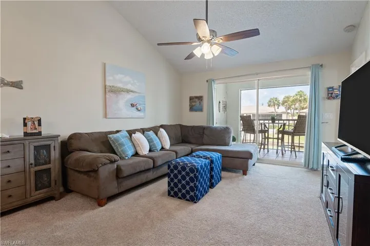 Living area with lofted ceiling, carpet floors, a textured ceiling, and a ceiling fan