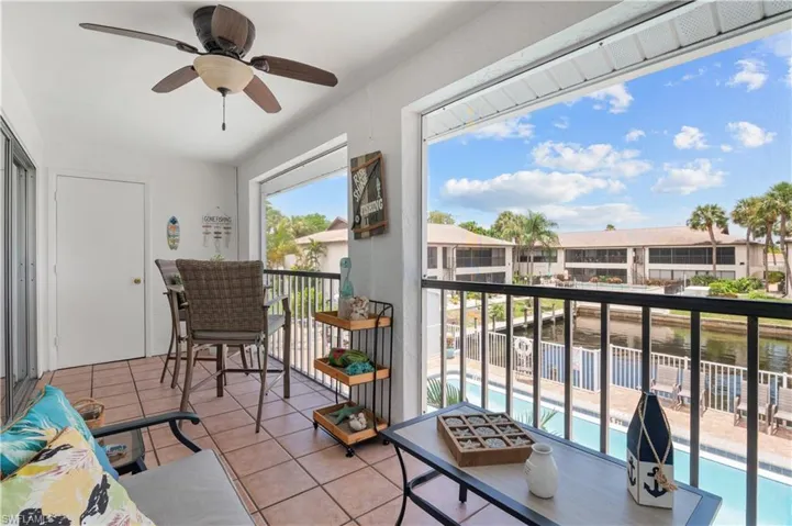 Balcony featuring view of pool, ceiling fan, and a water view