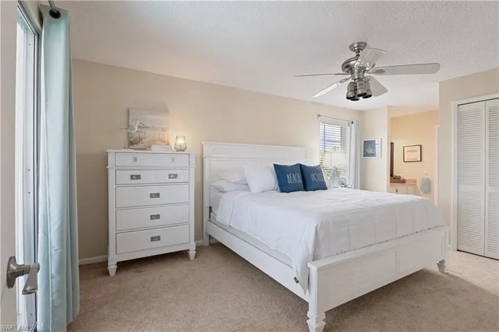 Bedroom featuring a closet, ceiling fan, a textured ceiling, and light colored carpet