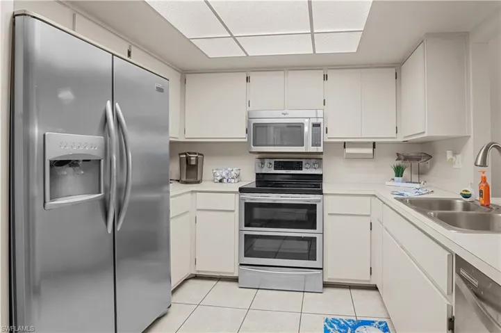 Kitchen featuring appliances with stainless steel finishes, white cabinets, and light countertops