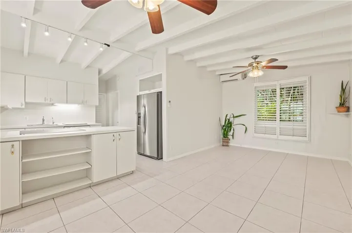 Dining area facing kitchen with stainless steel fridge with ice dispenser, light tile patterned floors, a ceiling fan, open shelves, and light countertops