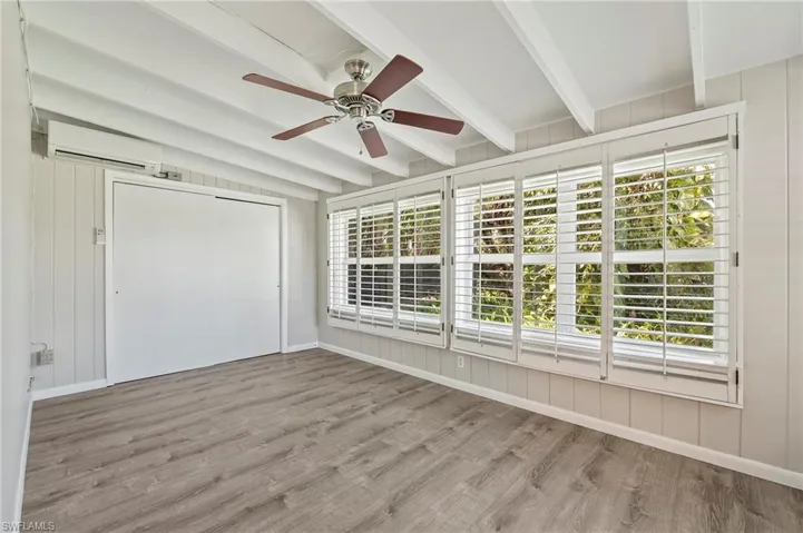 Unfurnished sunroom featuring a wall mounted air conditioner and beamed ceiling