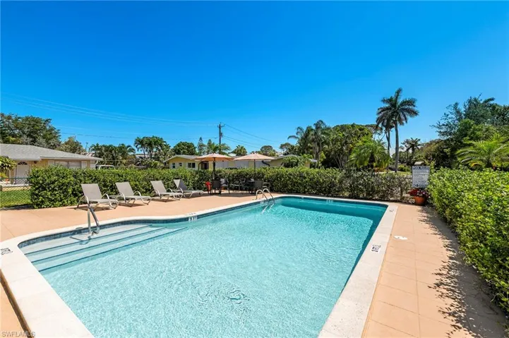 Community pool with a patio area and fence