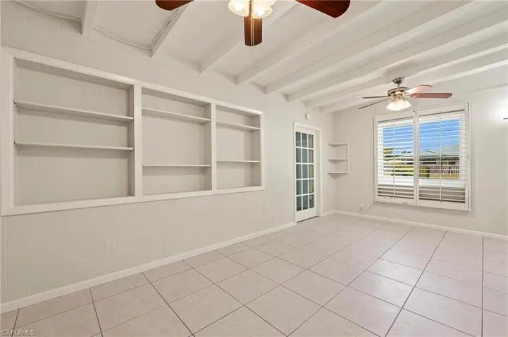 Empty room featuring baseboards, built in features, and ceiling fan