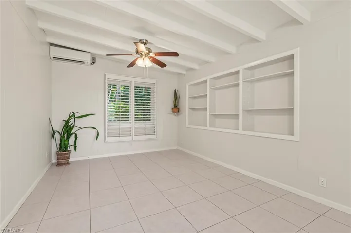 Spare room featuring light tile patterned floors, baseboards, a ceiling fan, and beam ceiling
