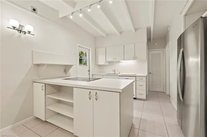 Kitchen featuring track lighting, light tile patterned floors, open shelves, freestanding refrigerator, and black electric stovetop