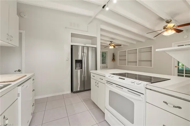 Kitchen with white appliances, light countertops, beamed ceiling, and ceiling fan