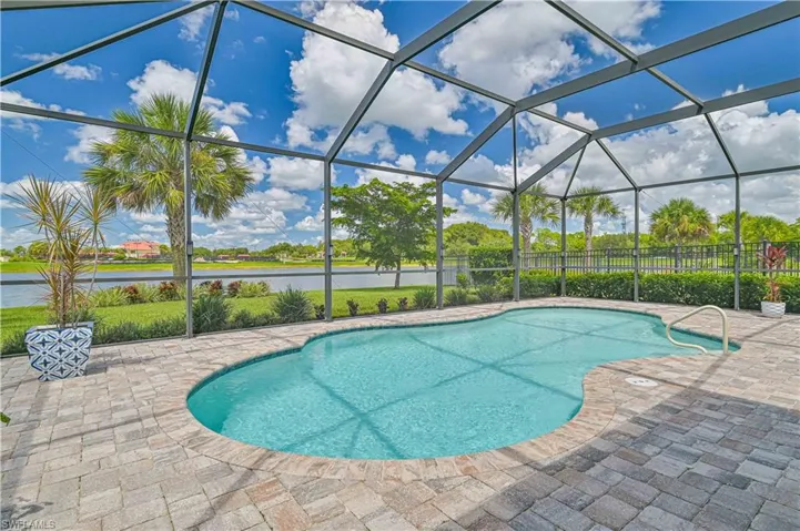 View of swimming pool with glass enclosure, a patio, and a water view