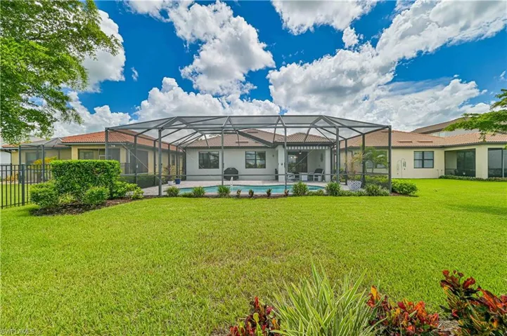 Back of property featuring a yard, a lanai, and a swimming pool