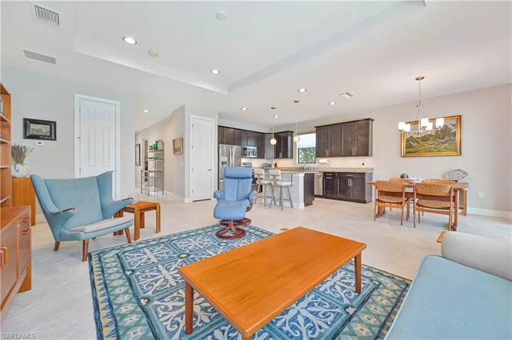 Living room with a raised ceiling, a notable chandelier, and light tile patterned floors