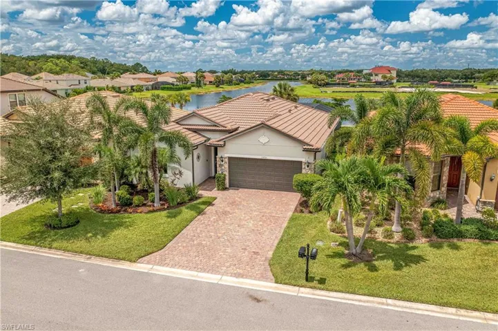 View of front of house with a front yard, a garage, and a water view