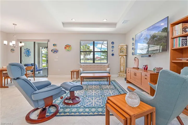 Living room featuring a raised ceiling, an inviting chandelier, and light tile patterned floors