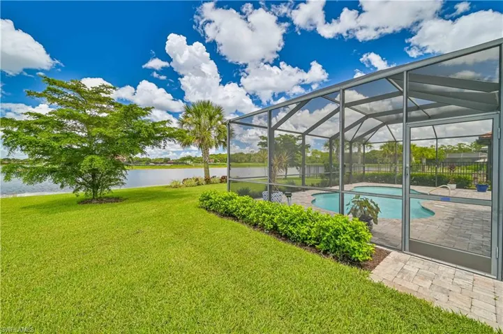 View of pool featuring a water view, a lawn, a lanai, and a patio area