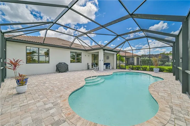 View of pool featuring glass enclosure, area for grilling, and a patio