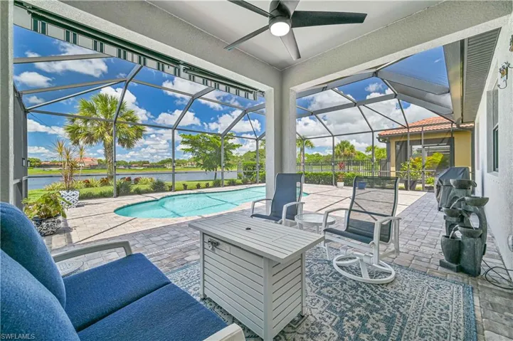 View of pool featuring a water view, ceiling fan, a lanai, and a patio