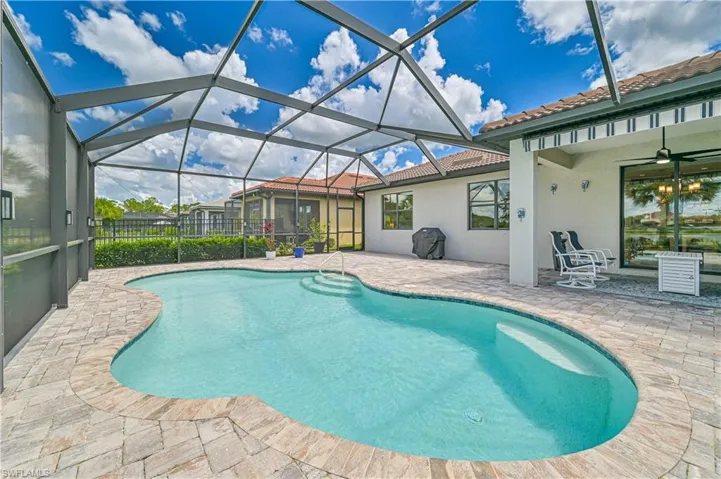 View of pool with ceiling fan, a patio, and glass enclosure