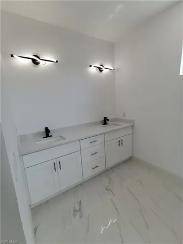 Full bath with double vanity and light marble finish floors