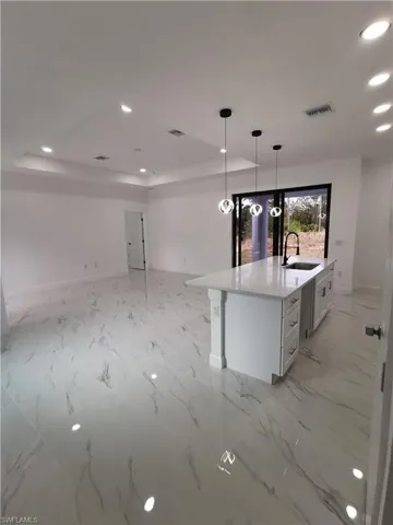 Kitchen with recessed lighting, open floor plan, light stone counters, pendant lighting, and white cabinetry
