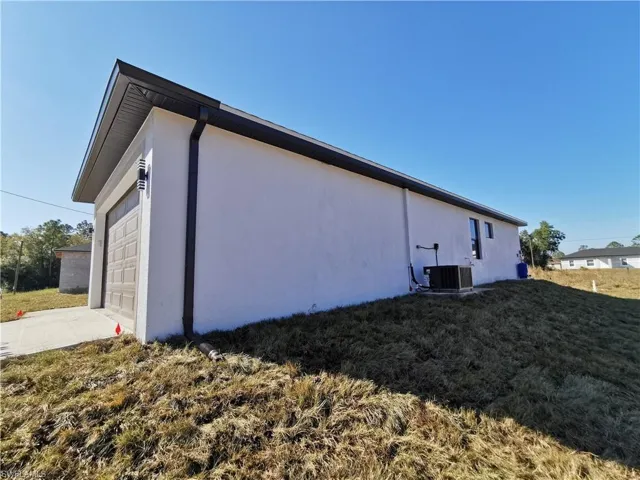 View of side of home featuring stucco siding, concrete driveway, a lawn, and a garage
