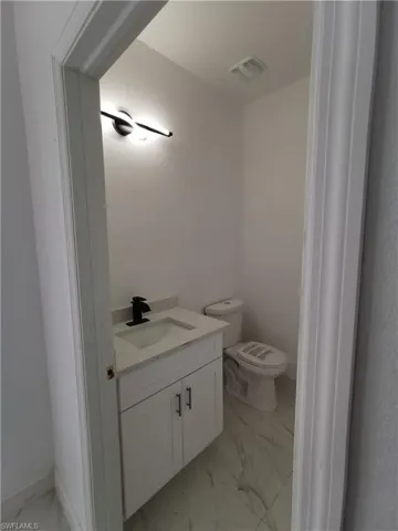 Half bathroom featuring light marble finish flooring and vanity