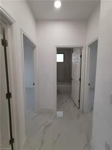 Hallway with light marble finish flooring and recessed lighting