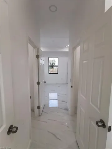 Hallway with light marble finish floors and baseboards